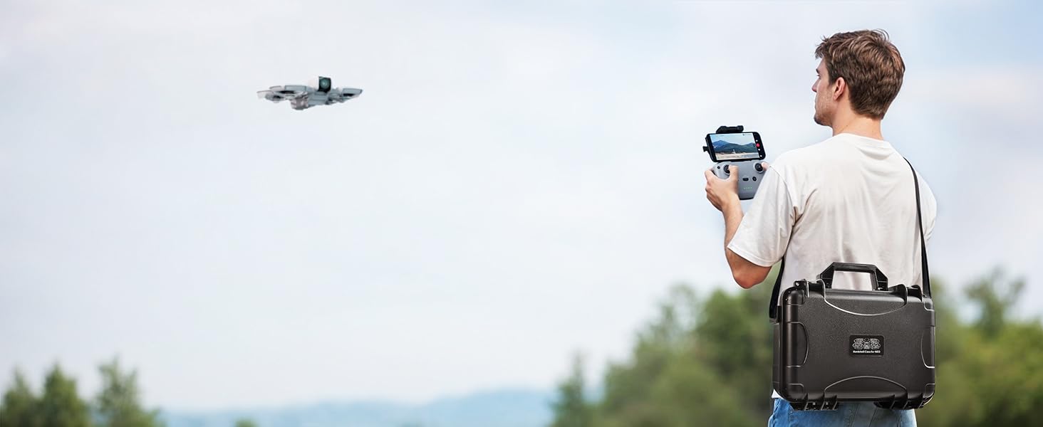 man flying the DJI neo with the hardcase strapped over his shoulder